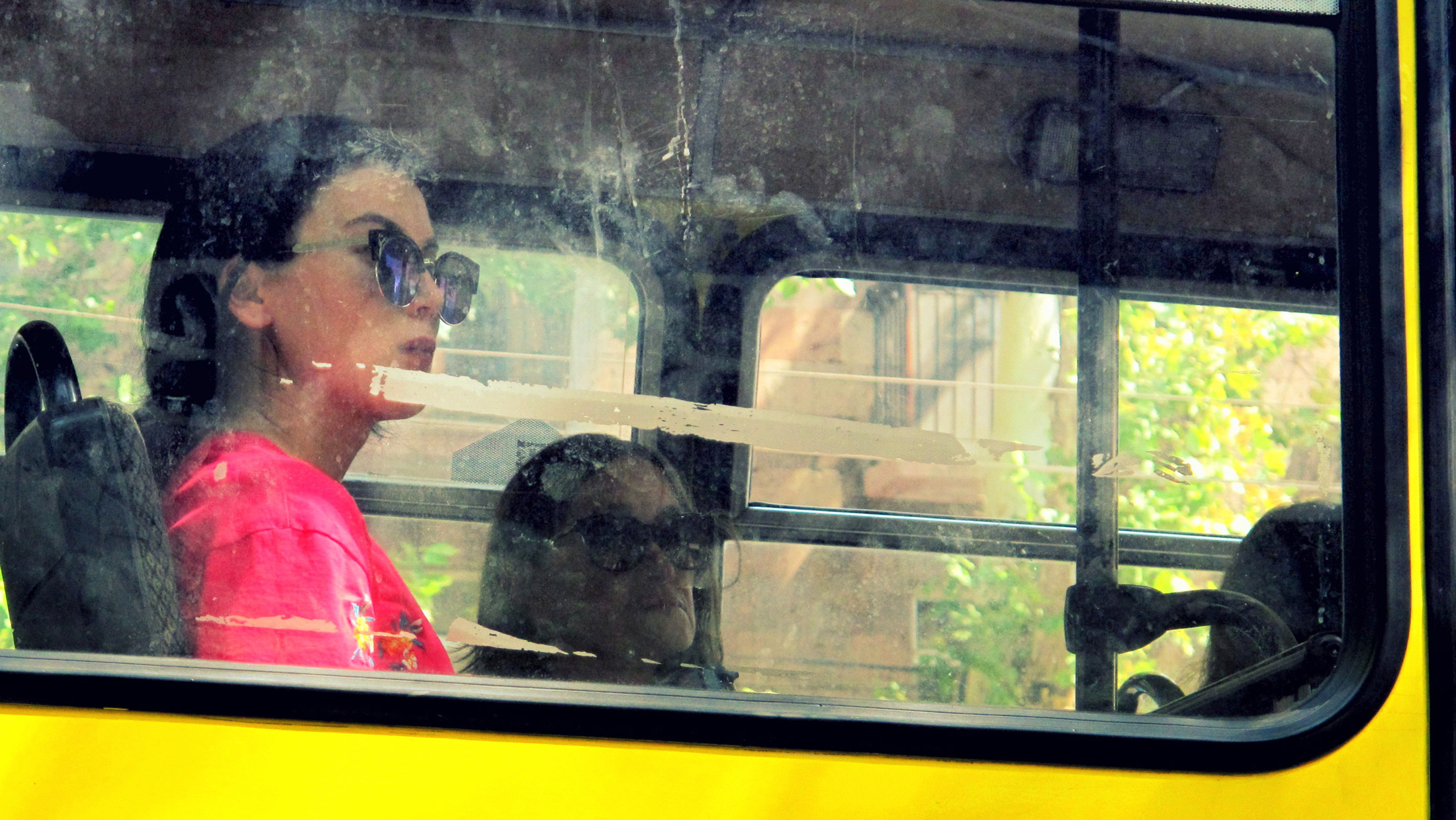 eine Frau mit Sonnenbrille sitz in einem Bus