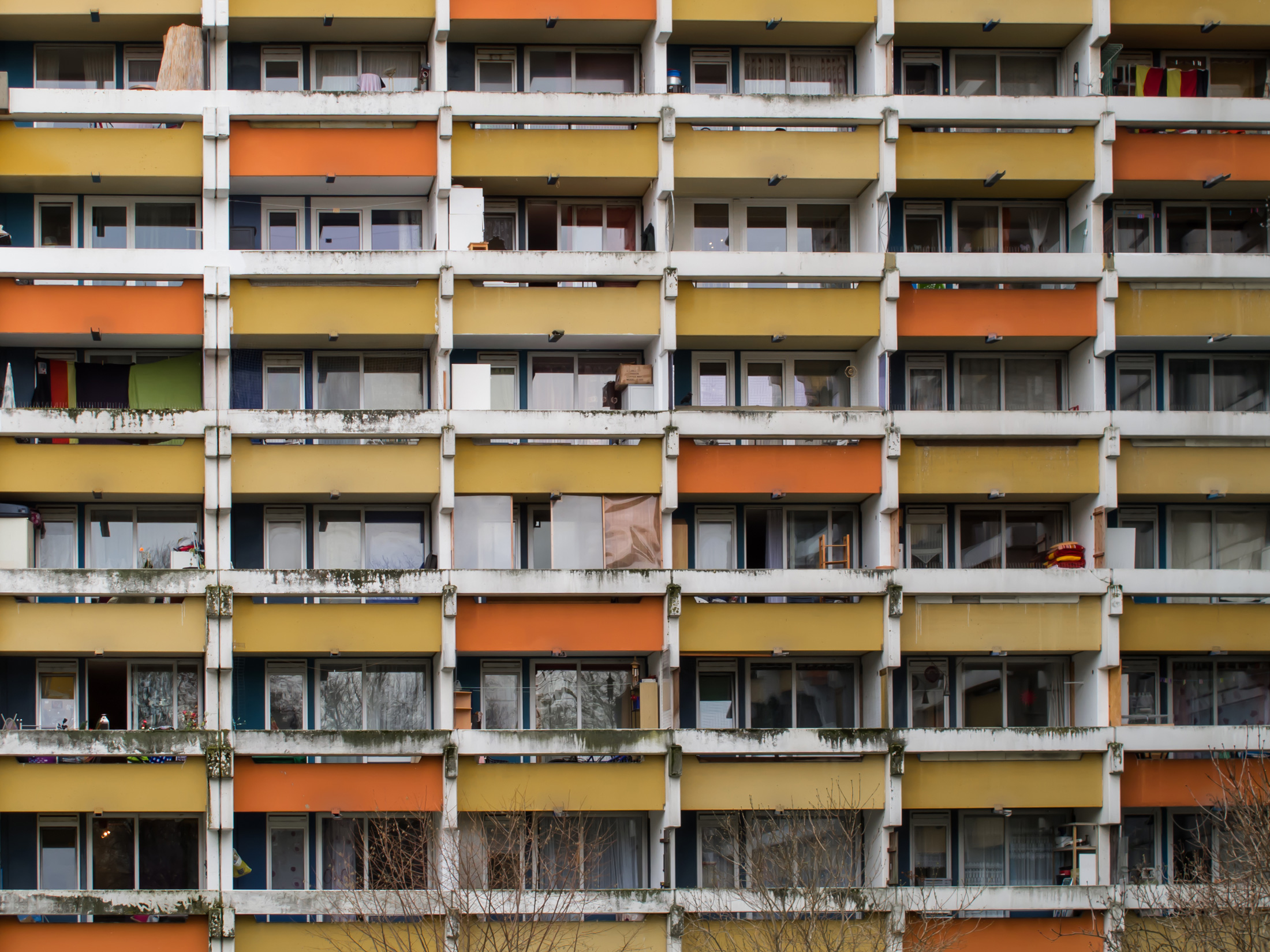 Häuserfassade mit ockergelben und orangenen Balkonen