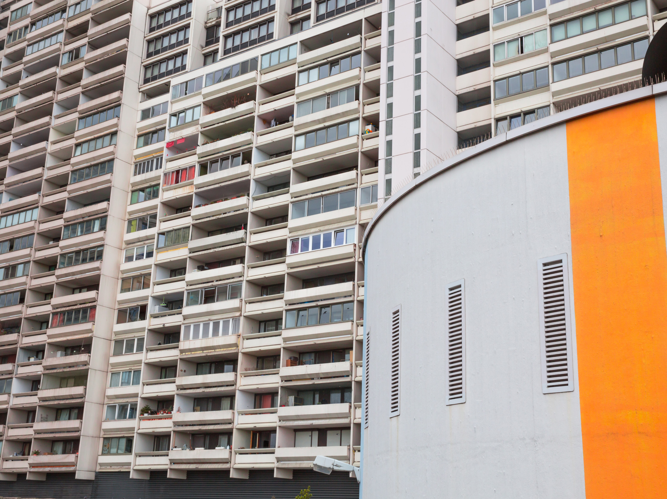 ein Rundbau mit orangenem Streifen vor einer Häuserfassade